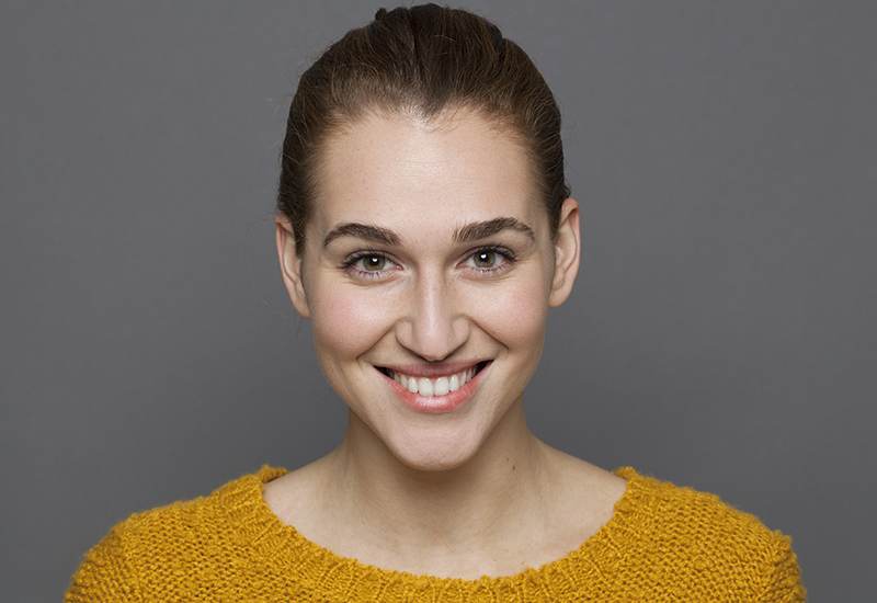 Brunette woman with her hair pulled back in a mustard color sweater